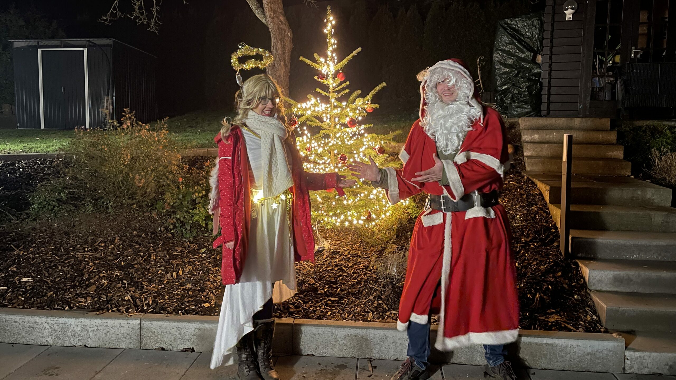 Weihnachtsmann und Christkind stehen vor einem Weihnachtsbaum.